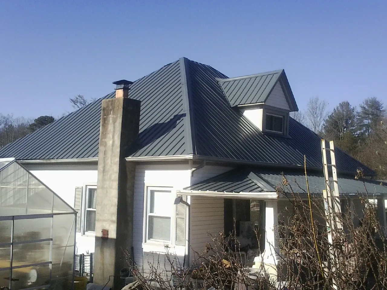 Dark blue standing seam metal roof on a white farmhouse with dormer — Slate & Tile Roof Repair by Roofing Brothers in Cumberland Foreside