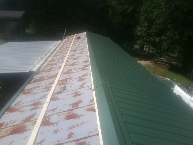 Old rusted panels beside newly installed green metal roofing — Wind Damage Roof Repair by Roofing Brothers in Cumberland Foreside