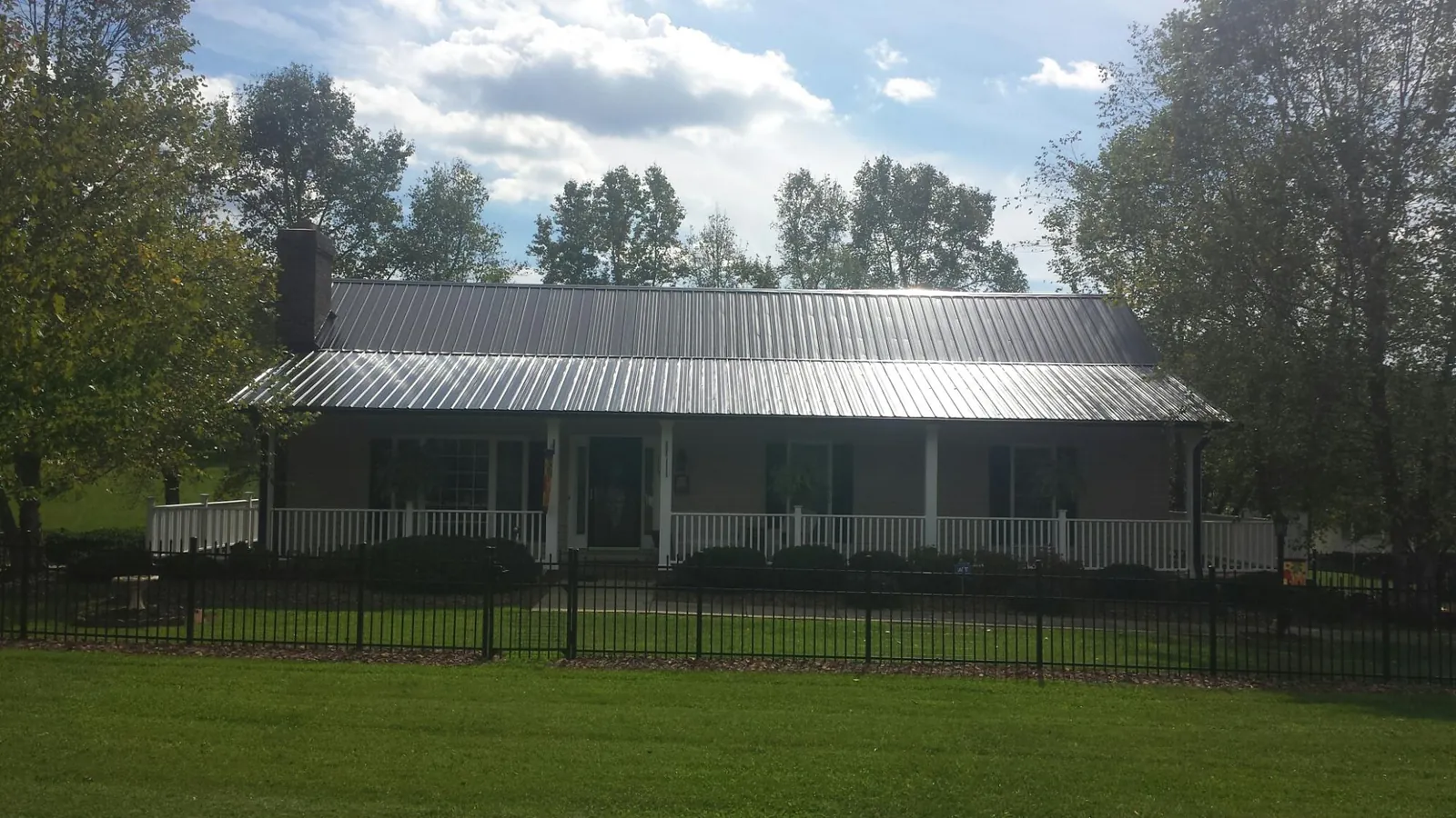 Gray metal roof on a brick ranch with a full width front porch — Gutter Guard Installation work by our crew in Cumberland Foreside